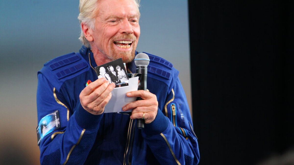 Richard Branson hält während der Pressekonferenz nach seinem Weltraumflug ein Foto seiner Eltern hoch