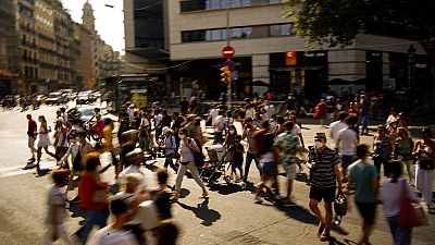 People wearing a face mask to protect against the spread of coronavirus walk along a street in downtown Barcelona, Spain, Saturday, July 3, 2021. 