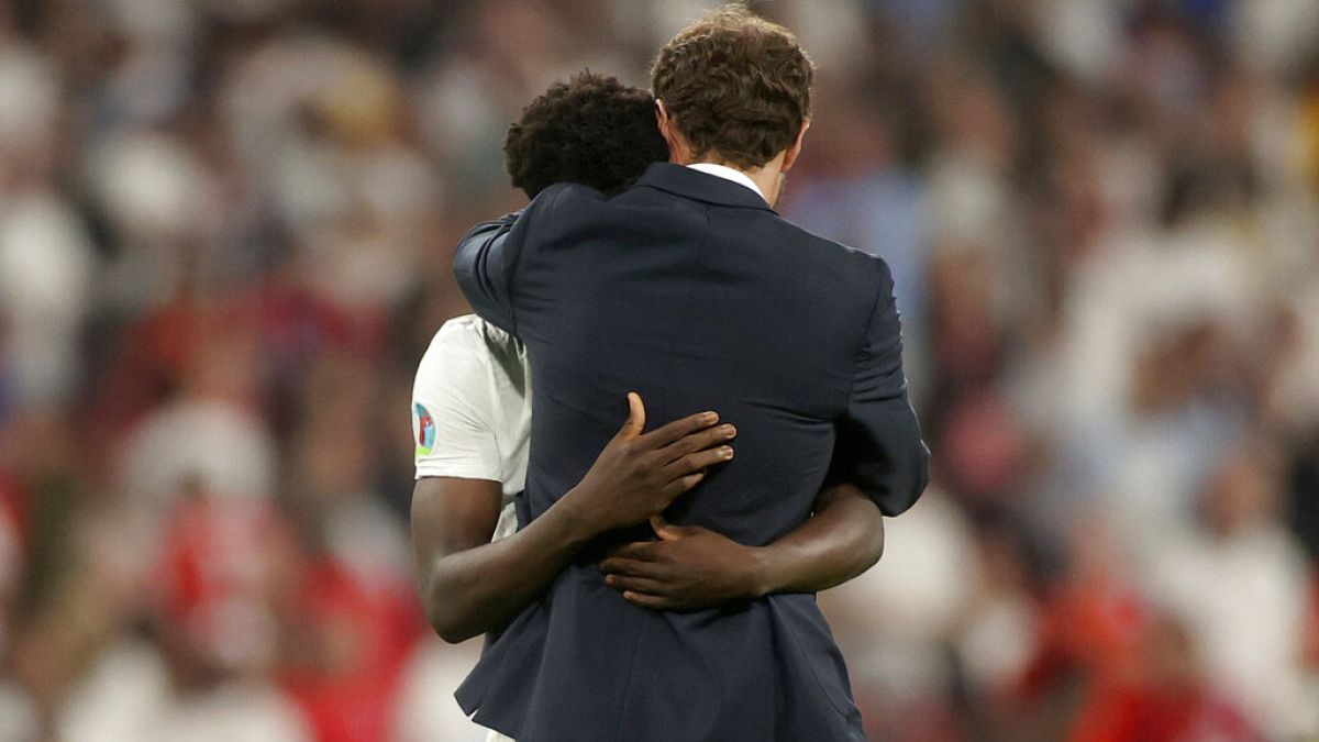 England's manager Gareth Southgate embraces Bukayo Saka after he failed to score a penalty during of the Euro 2020 final match at Wembley stadium in London,  July 11, 2021. 