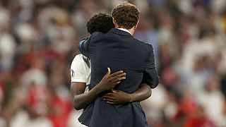 England's manager Gareth Southgate embraces Bukayo Saka after he failed to score a penalty during of the Euro 2020 final match at Wembley stadium in London,  July 11, 2021. 