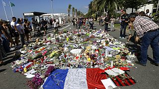 FILE - In this Monday July 18, 2016 file photo, people look at flowers placed on the Promenade des Anglais at the scene of a truck attack.