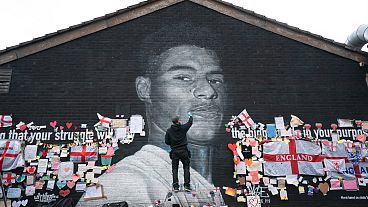 Street artist Akse P19 repairs a mural of Manchester United striker and England player Marcus Rashford in Withington, Manchester.