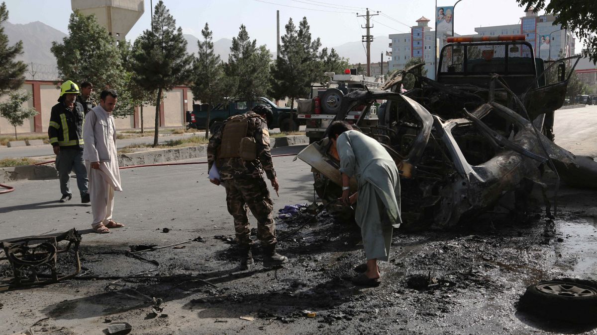 قوات الأمن الأفغانية تتفقد بقايا سيارة في موقع انفجار قنبلة في كابول في 12 يونيو 2021.