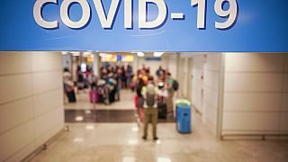 n this Aug.16, 2020 file photo, vacationers arriving in Rome from four Mediterranean countries, Croatia, Greece, Malta and Spain, line up with their suitcases at Rome airport.