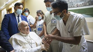 Pope Francis is greeted by hospital staff as he sits in a wheelchair inside the Agostino Gemelli Polyclinic in Rome, Sunday, July 11, 2021.