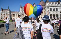 Activists wear shirts reading "Love is a human right" as they fly a giant heart balloon in rainbow colors in front of the parliament in Budapest