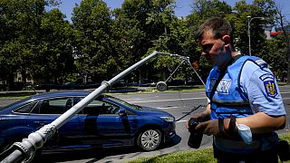 A Romanian gendarme takes pictures of a damaged car after a lamppost was knocked down by a U.S military Black Hawk helicopter following an emergency landing on a busy road