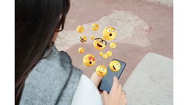 Woman using smartphone sending emojis