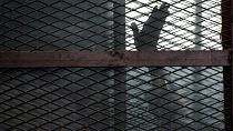Mısır'da bir mahkum, sanıkların savunma yaptıkları sırada konuldukları kafesten el sallarken