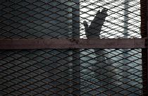 Mısır'da bir mahkum, sanıkların savunma yaptıkları sırada konuldukları kafesten el sallarken