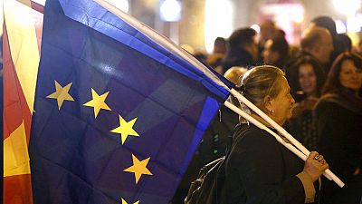 A woman holding the national and an EU flag takes a part in a rally titled "Walking for Justice," organized by the ruling Social Democrats, starting outside parliament in 2020