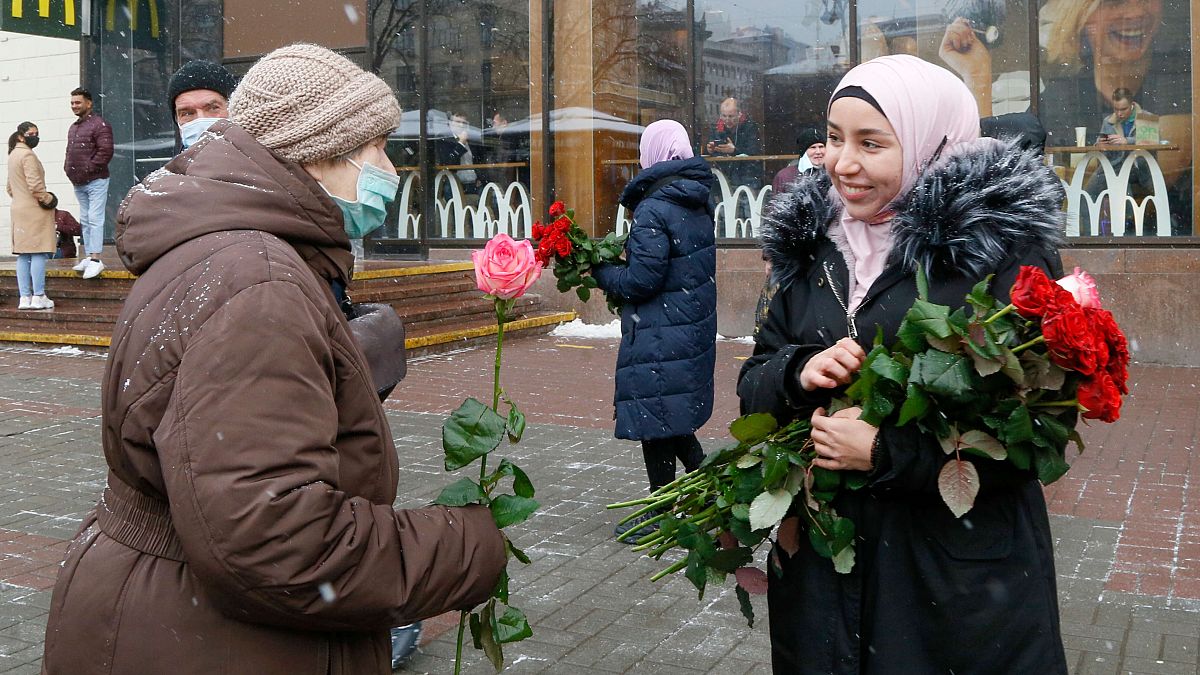 ناشطة ترتدي الحجاب تقدم زهرة لامرأة من المارة للاحتفال باليوم العالمي للحجاب في كييف، أوكرانيا، الاثنين 1 فبراير 2021. 