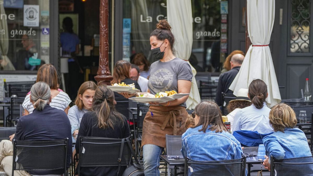 A waiter serves food at a restaurant terrace in Versailles, west of Paris, Thursday, July 15, 2021