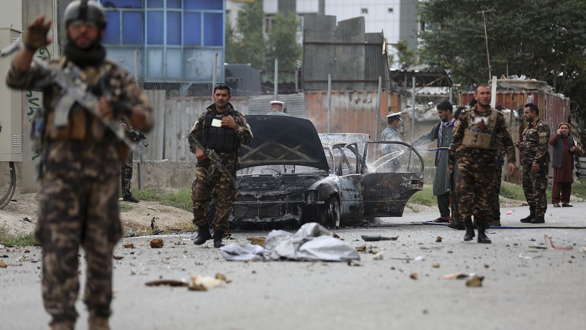 Des personnels de sécurité inspectent un véhicule endommagé alors que trois roquettes ont été tirées près du palais présidentiel à Kaboul, le 20 juillet 2021