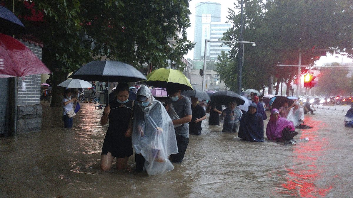 People move through flood water after a heavy downpour in Zhengzhou city, central China's Henan province on Tuesday, July 20, 2021. 