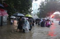 People move through flood water after a heavy downpour in Zhengzhou city, central China's Henan province on Tuesday, July 20, 2021. 