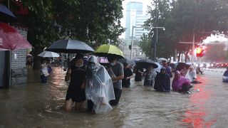 People move through flood water after a heavy downpour in Zhengzhou city, central China's Henan province on Tuesday, July 20, 2021. 