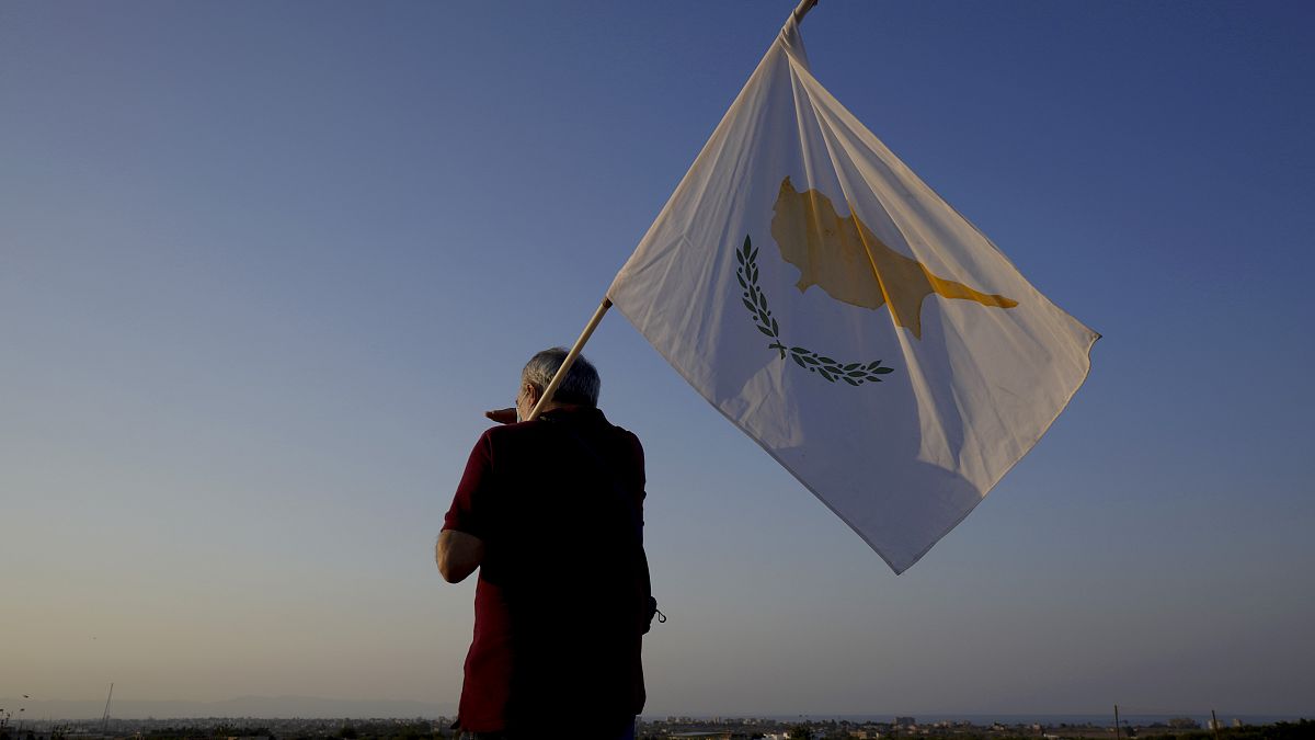 رجل يحمل علم قبرص يقف أمام فاروشا أو فاماغوستا، المدينة المهجورة   في قبرص.