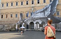 Des passants regardent l'oeuvre de JR sur la façade du palais Farnese à Rome