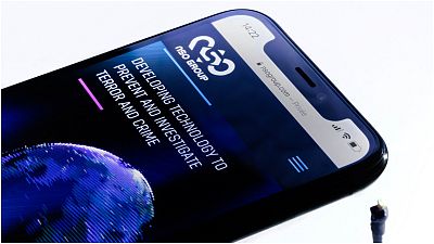 رسمي توضيحي يبين هاتف ذكي وعلى شاشته يظهر موقع الويب الخاص بمجموعة "إن إس أو" الإسرائيلية والذي يعرض برنامج تجسس "بيغاسوس"