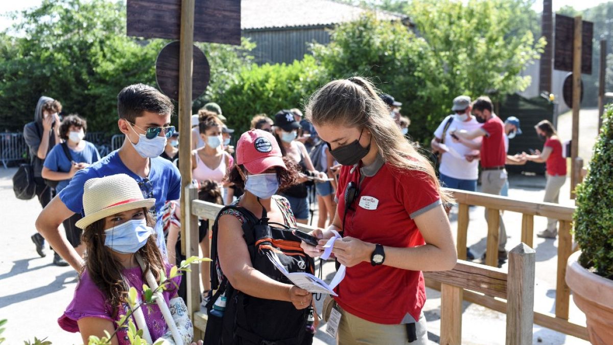 An employee checks a visitors health pass at the entrance of the Puy du Fou theme park in Les Epesses, France