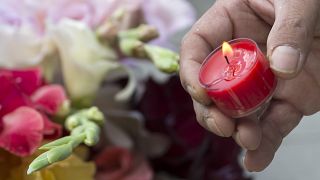 A man lights a candle beside the Olympia shopping centre in Munich.