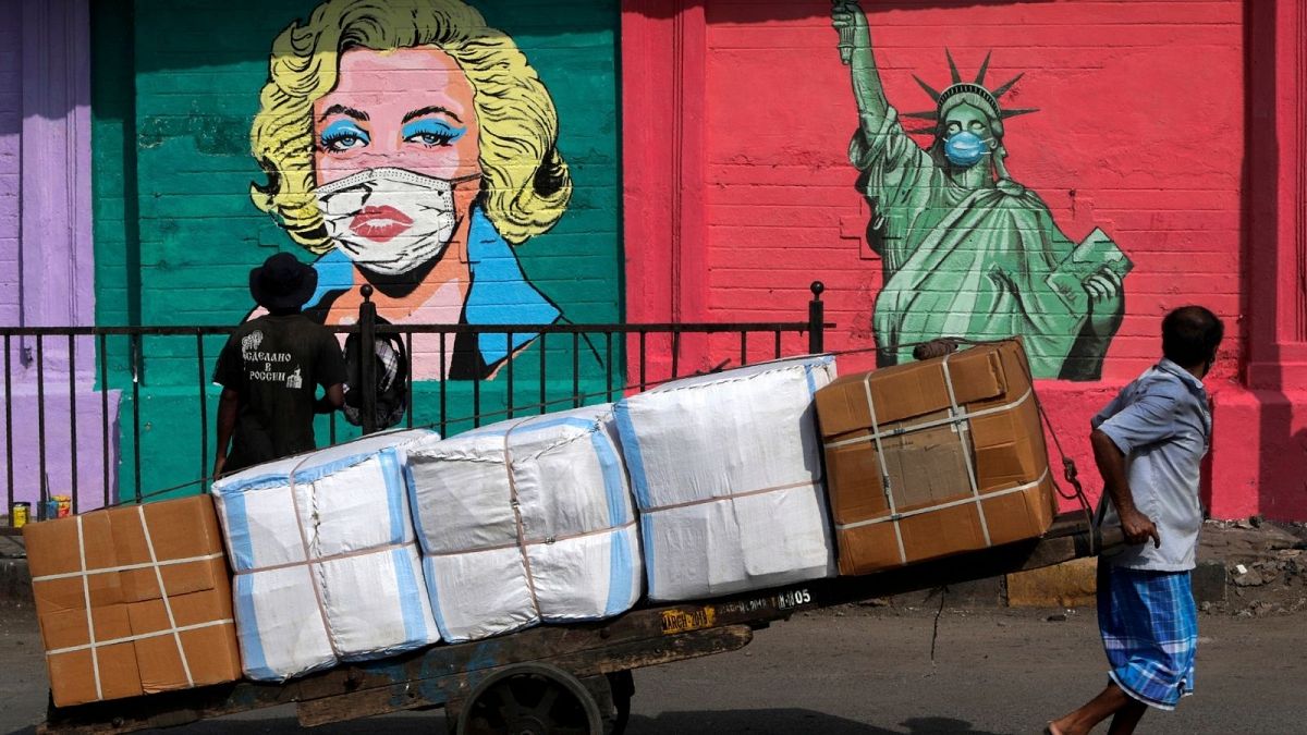 کارگر هندی محو تماشای نقاشی دیواری از مجسمه آزادی و مرلین مونروی ماسک زده