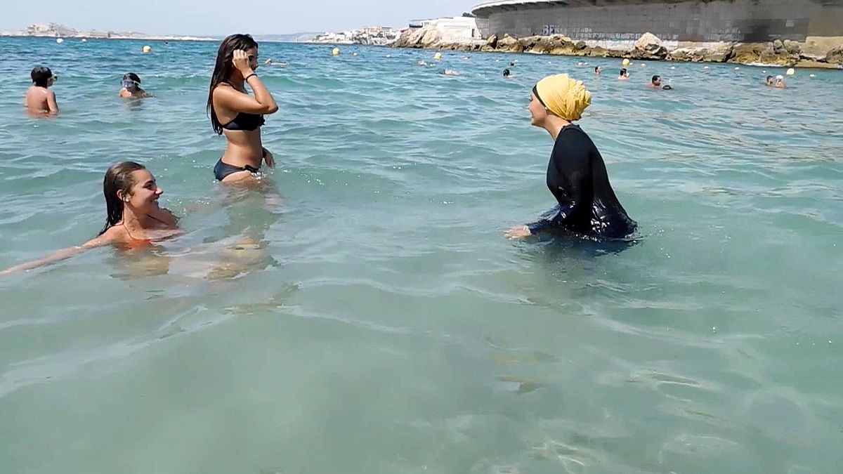 Imágen de archivo de 2016: Nesrine Kenza, que dice estar feliz de ser libre de llevar un burkini, y dos amigos no identificados se adentran en el mar, en Marsella, Francia.