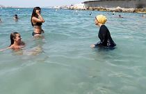 Imágen de archivo de 2016: Nesrine Kenza, que dice estar feliz de ser libre de llevar un burkini, y dos amigos no identificados se adentran en el mar, en Marsella, Francia.