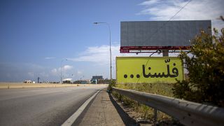 لافتة مكتوب عليها "فلسنا" على طريق سريع رئيسي فارغ، يربط بيروت بمدينة طرابلس، لبنان.