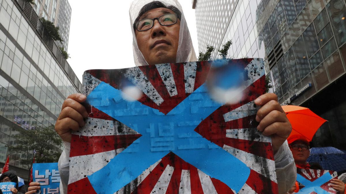 Güney Kore'nin başkenti Seul'de Japonya'nın imparatorluk dönemi kullandığı "doğan güneş" temalı bayrağı protesto eden bir vatandaş. 
