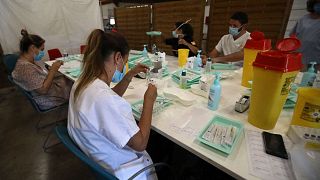 يقوم العاملون الصحيون بإعداد الحقن التي تحتوي على جرعة من لقاح كوفيد-19 في مركز التطعيم في بربينيان، جنوب فرنسا، 18 يوليو 2021