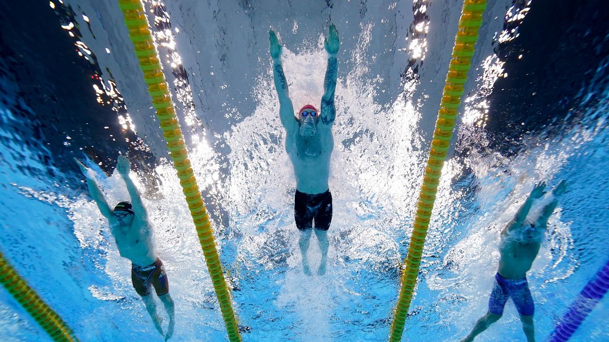 Britain's Adam Peaty, center, swims to win the gold medal in the 100-meter breaststroke final at the 2020 Summer Olympics, July 26, 2021, in Tokyo.
