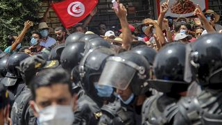 محتجون يقفون أمام عناصر الشرطة التونسية خلال مظاهرة في العاصمة تونس. 2021/07/25 