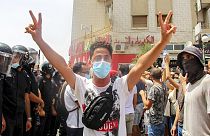Demonstrátor mutatja a győzelem jelét Tuniszban a tunéziai rendőrség sorfala mellett július 25-én