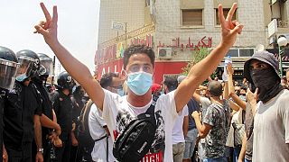Demonstrátor mutatja a győzelem jelét Tuniszban a tunéziai rendőrség sorfala mellett július 25-én