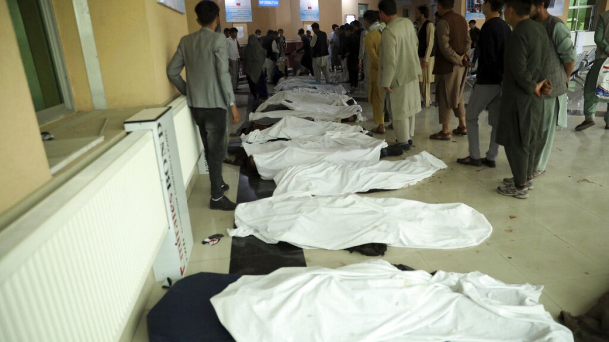  رجال أفغان يحاولون التعرف على الجثث في مستشفى بعد انفجار قاتل بالقرب من مدرسة غرب كابول، أفغانستان.