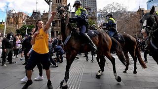 A protester tries to push away a police horse in Sydney during anti-lockdown protests, July 2021 