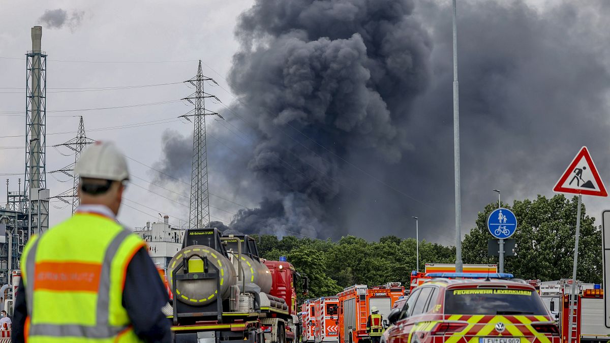 Emergency vehicles stand not far from an access road to the Chempark over which a dark cloud of smoke is rising in Leverkusen, Germany, July 27, 2021.