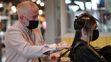 Salon owner and hairdresser Adam Reed cuts a client's hair at his salon in Spitalfields, East London on July 1, 2021.