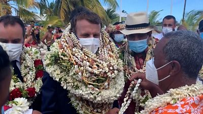 Emmanuel Macron is welcomed with garlands of flowers and seashells.