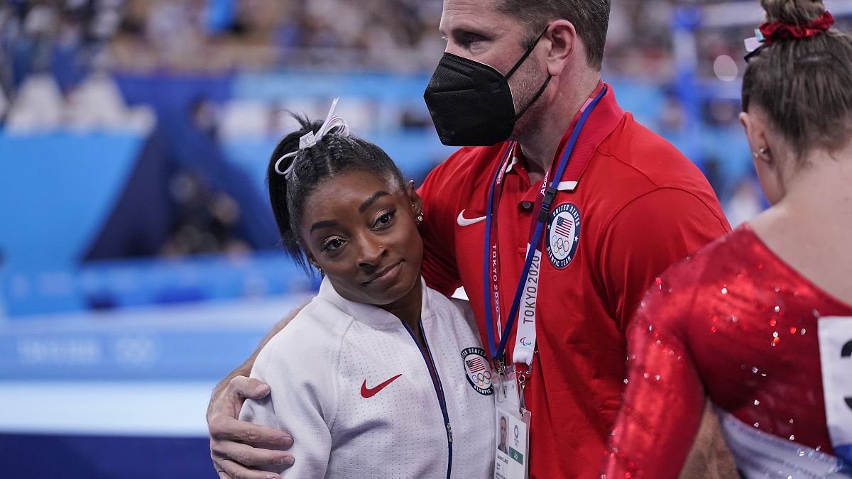 Coach Laurent Landi embraces Simone Biles, after she exited the team final, at the 2020 Summer Olympics, Tuesday, July 27, 2021, in Tokyo