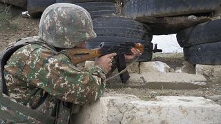 Un soldado armenio sostiene una ametralladora Kalashnikov mientras mira hacia las posiciones de Azerbaiyán