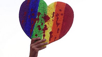 A protester holds up a heart with the rainbow colours splattered with red paint during a demonstration to protest against LGTBQ-phobia in Madrid