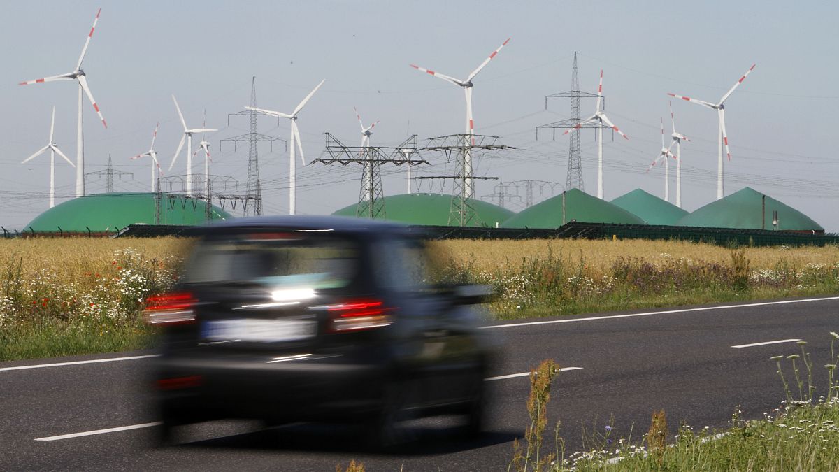 A car passes by a biogas plant and windmills near Nauen, Germany. 