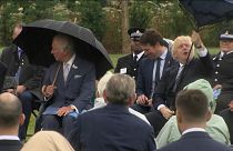  UK Prime Minister Boris Johnson struggles with umbrella as he sits with Prince Charles at a dedication ceremony for a police memorial.