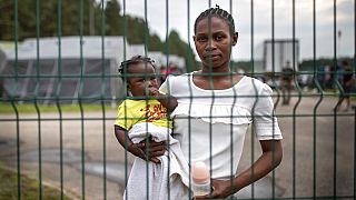 FILE: Towe Mahawa, a migrant from Guinea, holds her daughter Kadaitou as she looks through a fence at the refugee camp in Druskininkai, some 145km south from Vilnius,