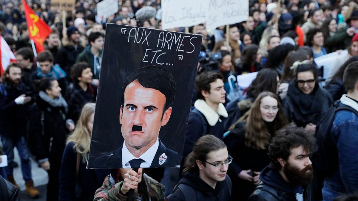 A person holds a placard depicting French President Emmanuel Macron as Adolf Hitler during a 2018 protest against a proposed university reform.
