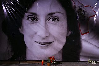 Flowers and a candle lie in front of a portrait of slain investigative journalist Daphne Caruana Galizia during a vigil outside the law courts in Valletta, Malta.