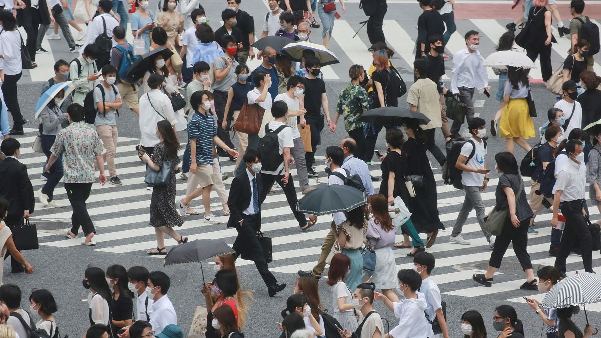 People wearing face masks cross a street in Tokyo